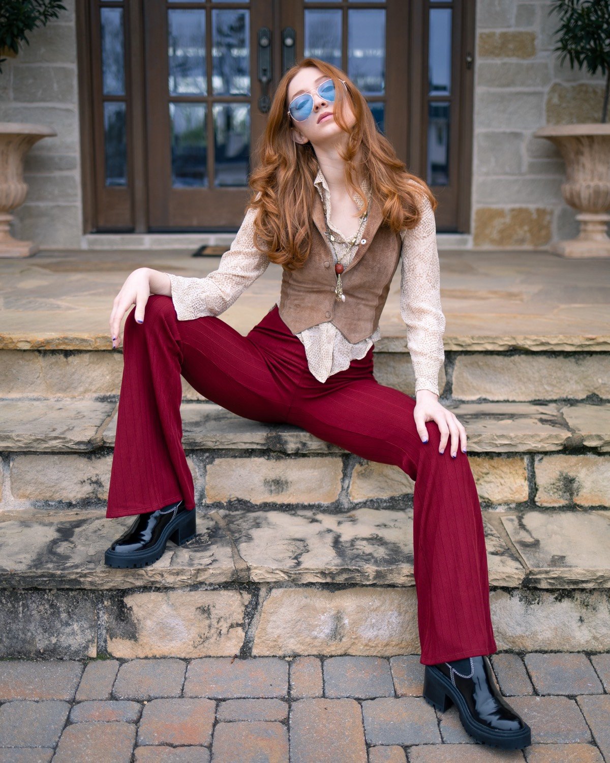 Melissa in 70s look — suede vest, burgundy flares, blue aviators