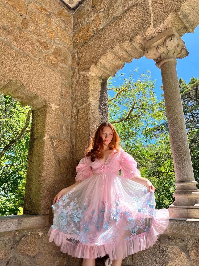 Melissa in pink butterfly dress in a stone archway